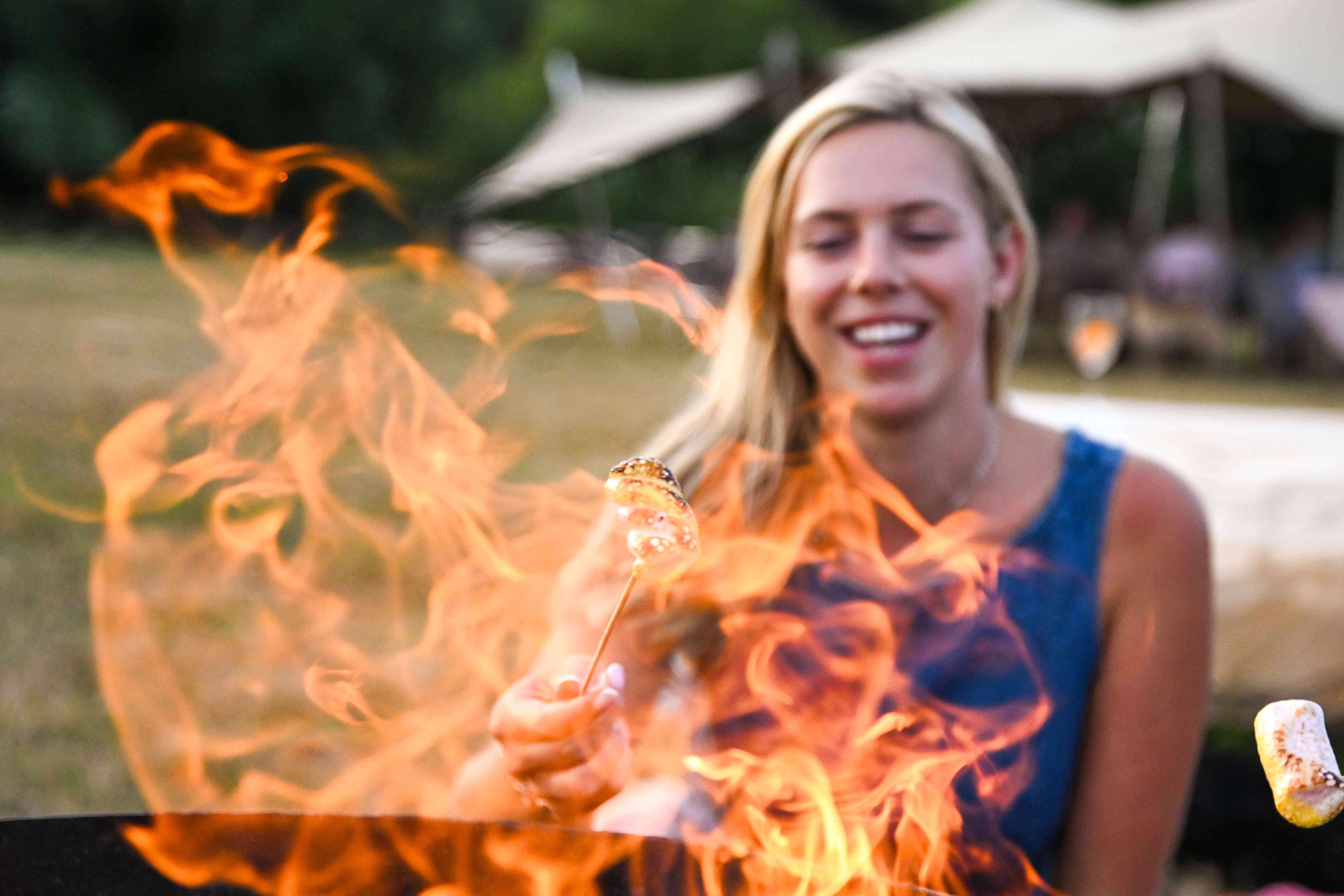 Girl toasting a marshmallow on a stick at Hopnest glamping fire pit